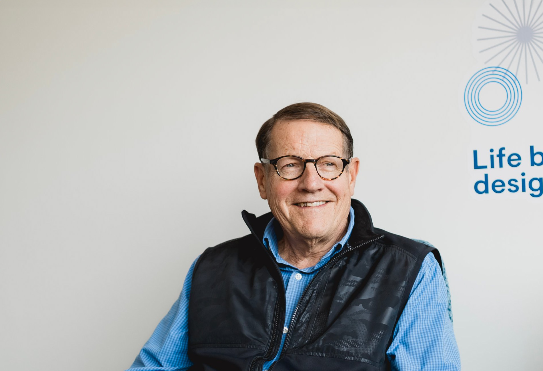Bob Hanft, Senior Strategic Financial Advisor. A man wearing a blue button down and vest against a white wall. Company headshot photo.