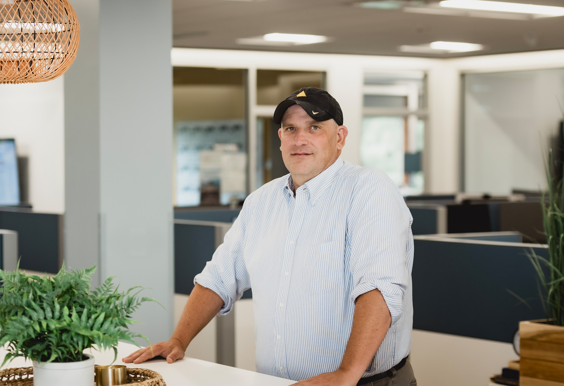 Jeremy Stewart, Chief Technology Officer: A man wearing a blue button down and a black baseball hat. company website bio page photo headshot.
