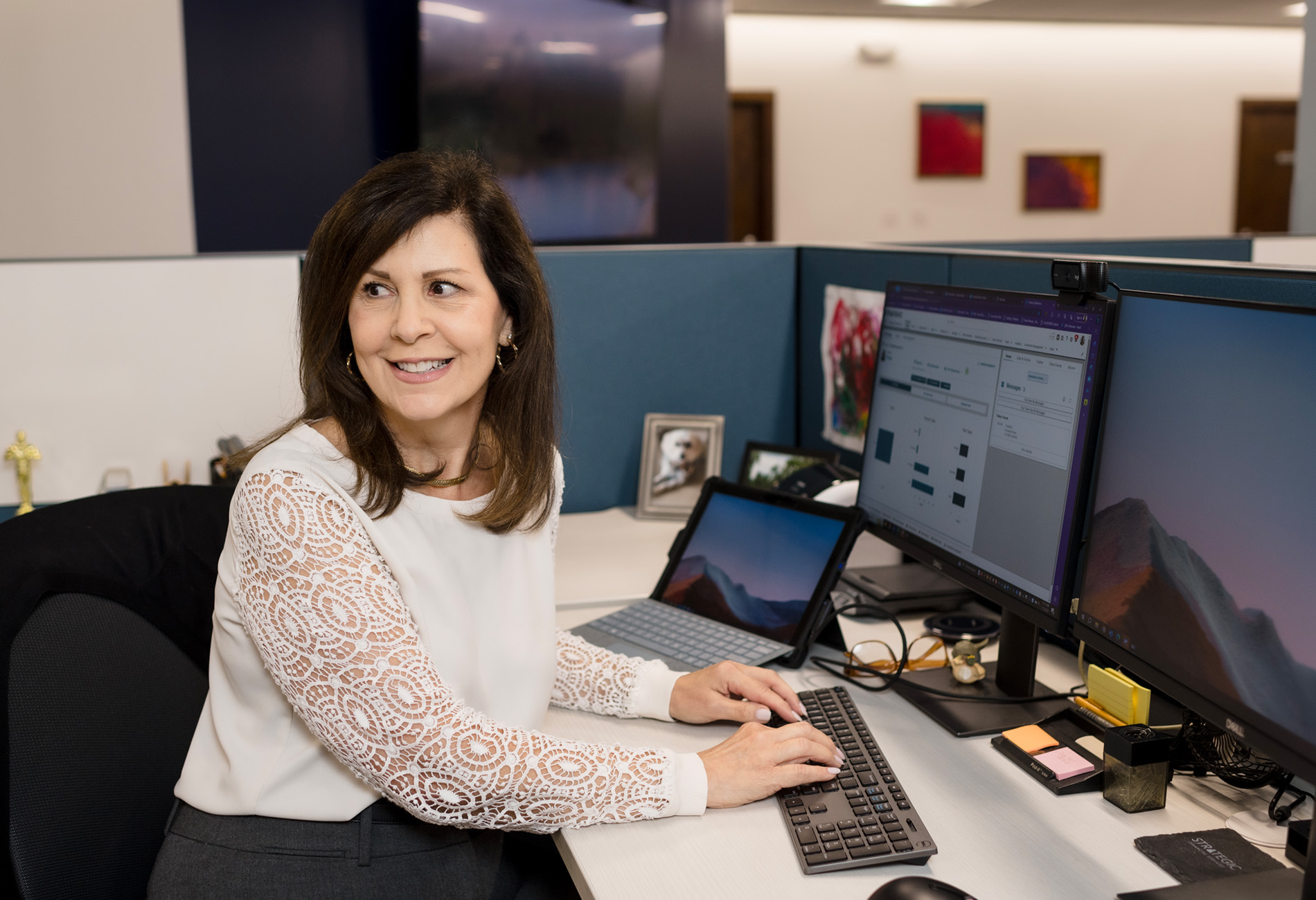 Paula Rizzo, Senior Client Service Specialist: A woman with long brown hair and a white blouse working at her computer.